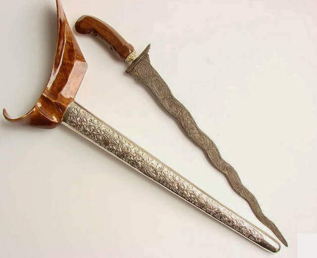 Keris dengan bilah berlekuk dan hiasan pada bilah serta gagang.